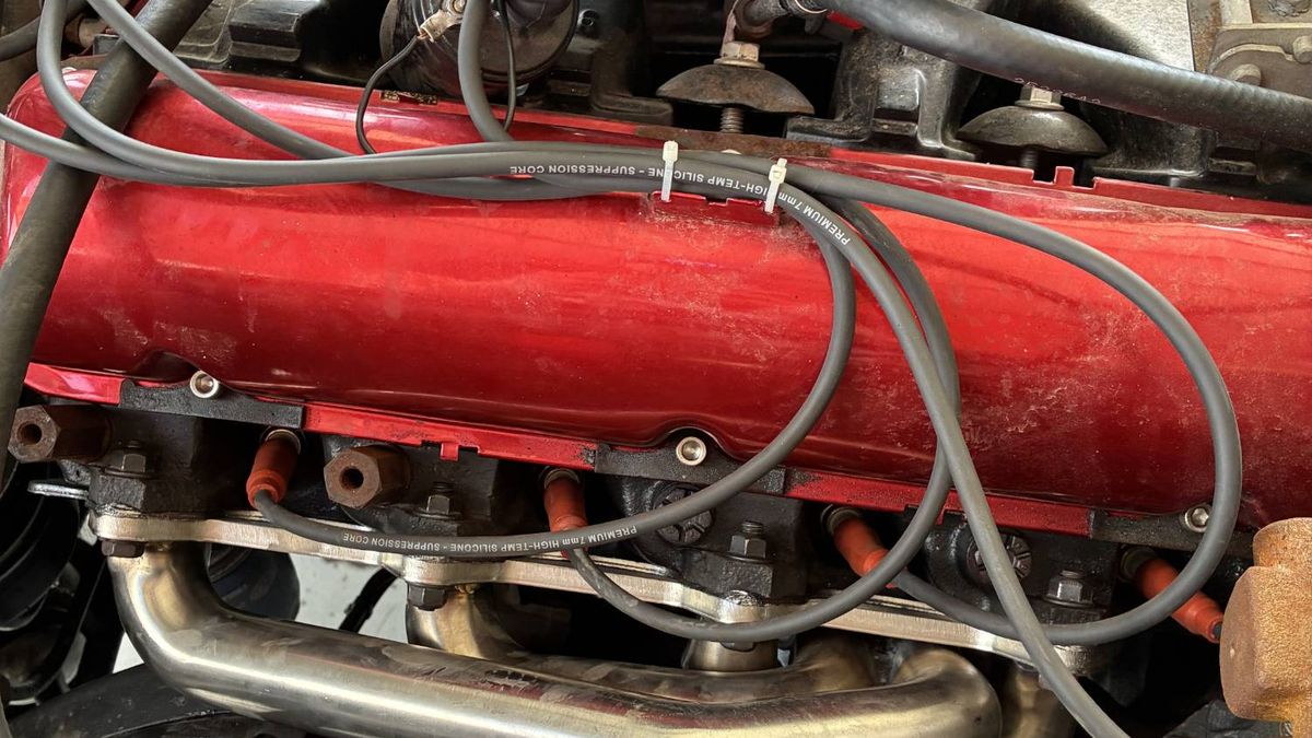 High-temp plug wires routed over a red valve cover, with stainless headers below