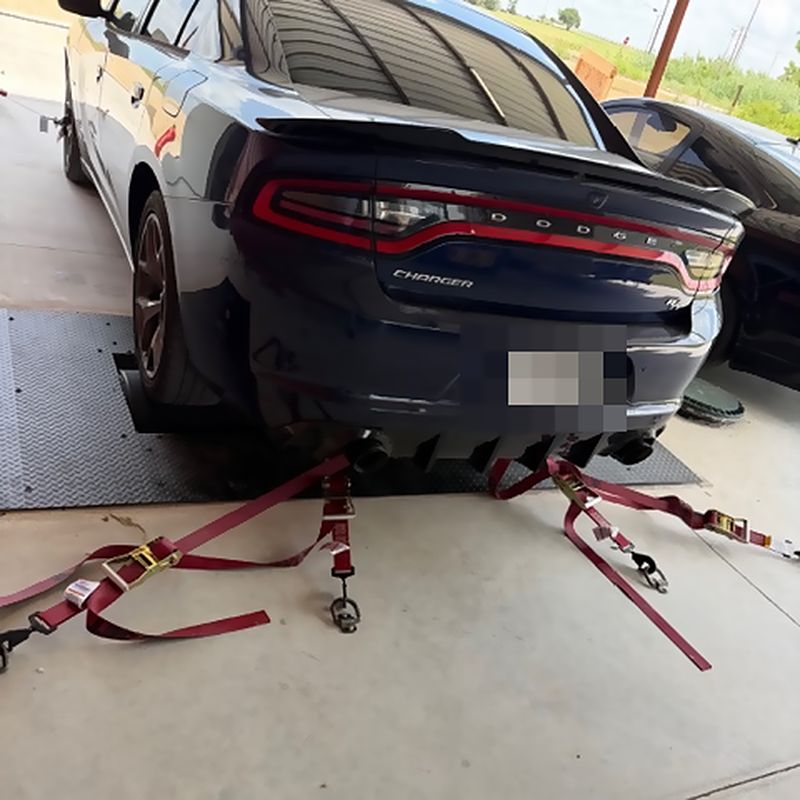 A Dodge Charger strapped to the dyno rollers by its chassis